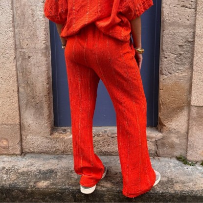 Pantalon orange brodé vue de derrière et porté par une femme