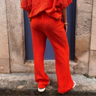 Pantalon orange brodé vue de derrière et porté par une femme