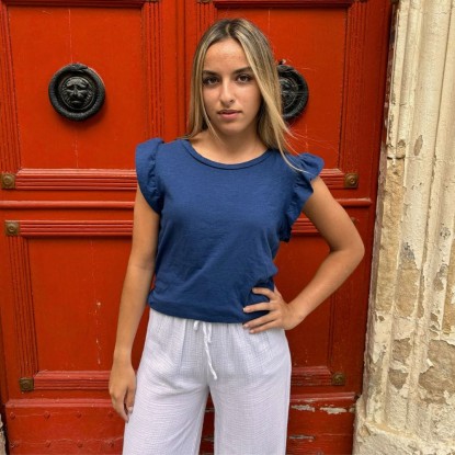 Top à volants Marie île de Ré de couleur blanc vue de face et porté par une femme avec un pantalon blanc