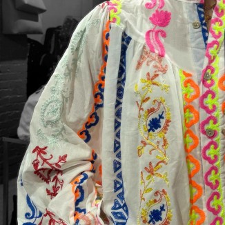 blouse Garance vue de près avec ses détails colorés dans un miroir et portée par une fille