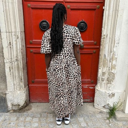 Robe leo léopard vue de derrière et portée par une femme devant une porte rouge