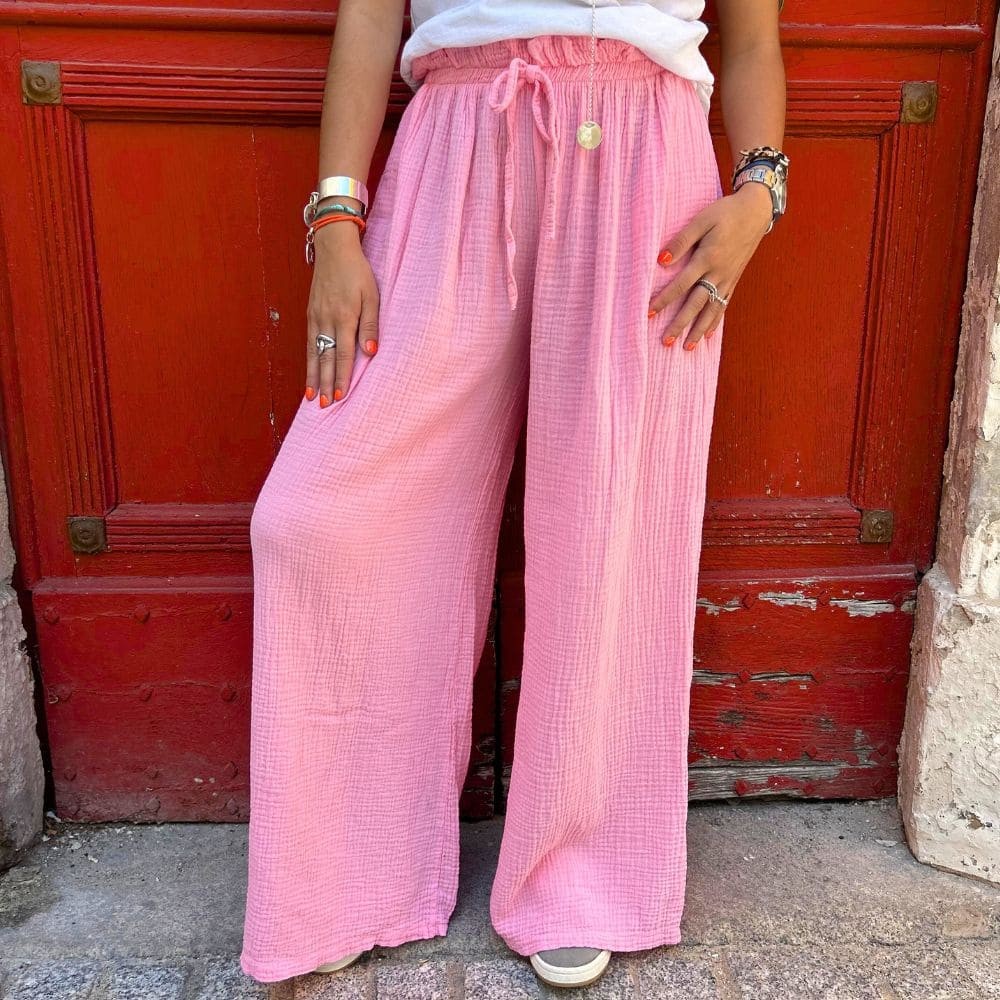 Pantalon en gaze de coton de couleur rose clair vue de face et porté par une femme